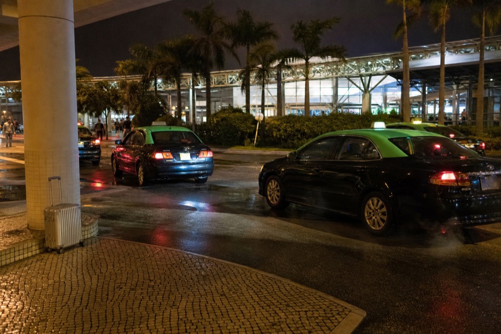 Macau taxi rank at night with a ferry terminal in the background