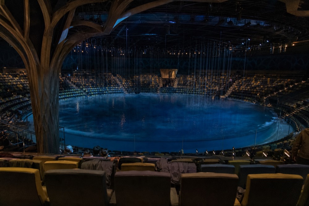 Theatre auditorium with a large pool stage lit in deep blue before a performance