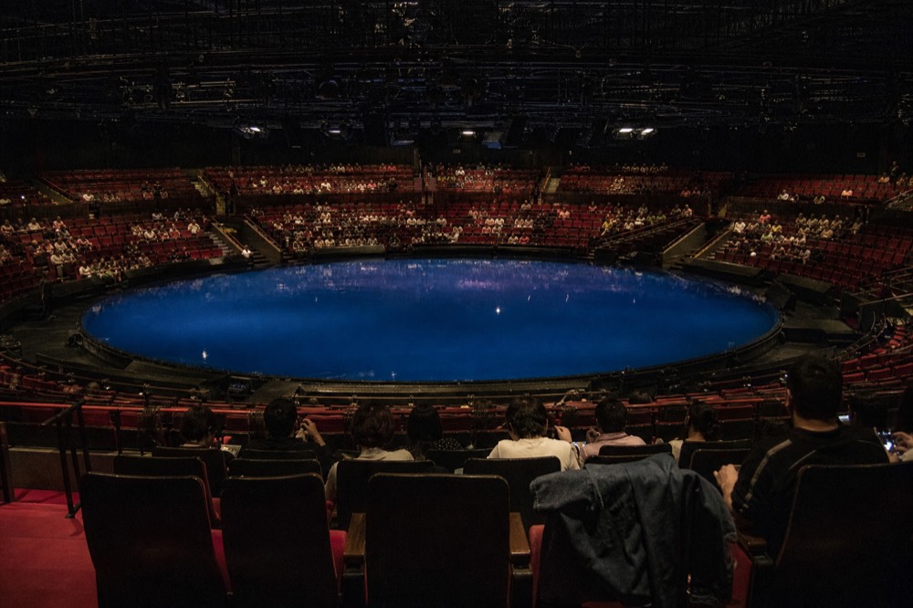 Theatre auditorium with a large pool stage lit in blue before a performance