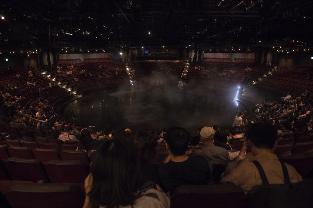 Auditorium of a large theatre in the round before an evening performance