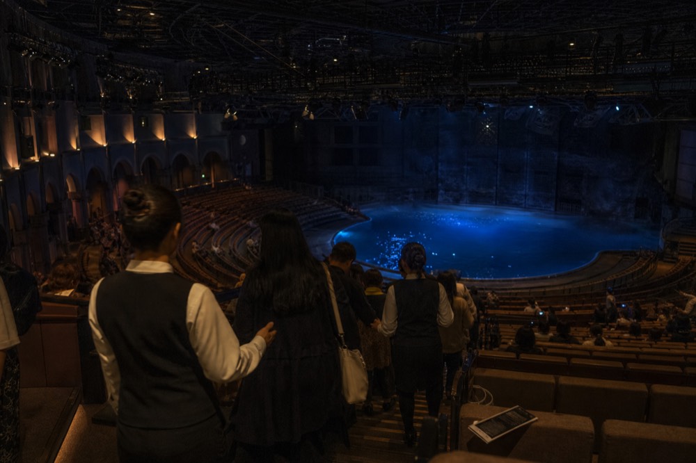 Audience taking seats in a theatre-in-the-round before a performance