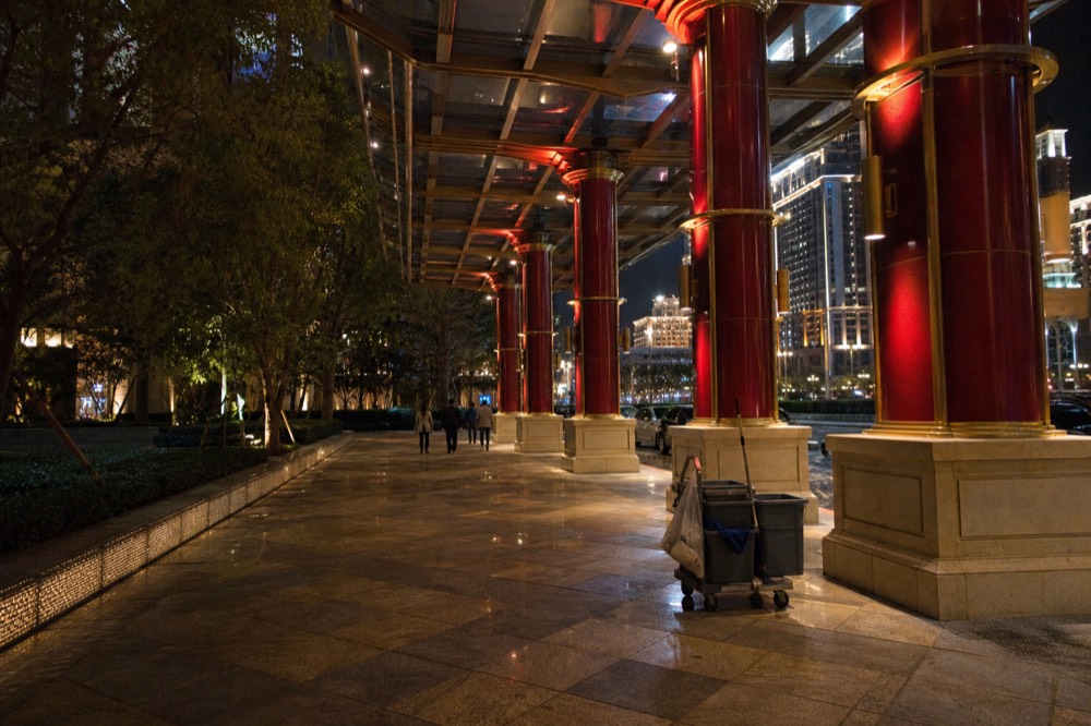 Covered walkway and promenade between illuminated Cotai resort facades at night