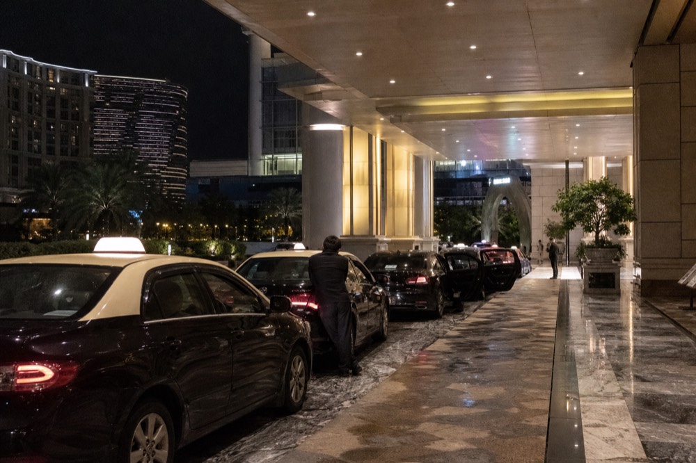 Taxi queue with metered cars at a lit Cotai resort entrance at night