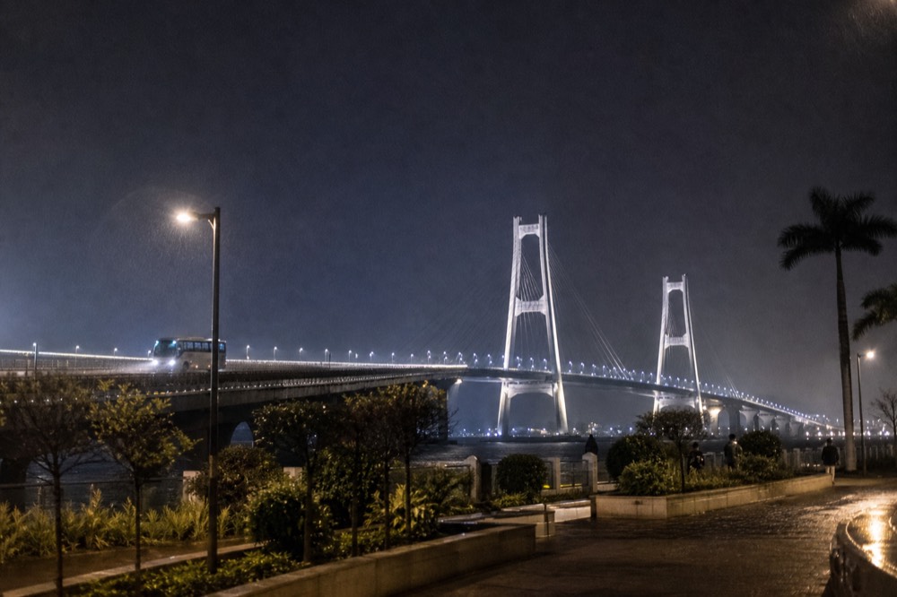 A lit bridge stretching across dark water at night