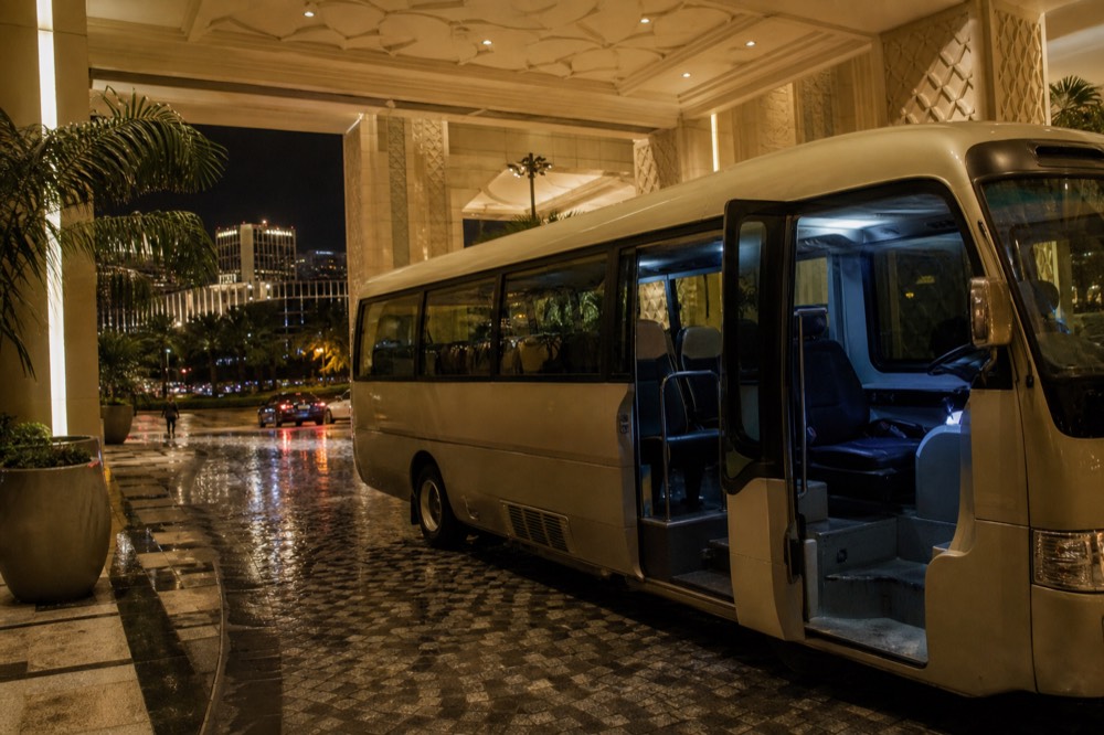 A resort shuttle bus parked under a covered entrance at night