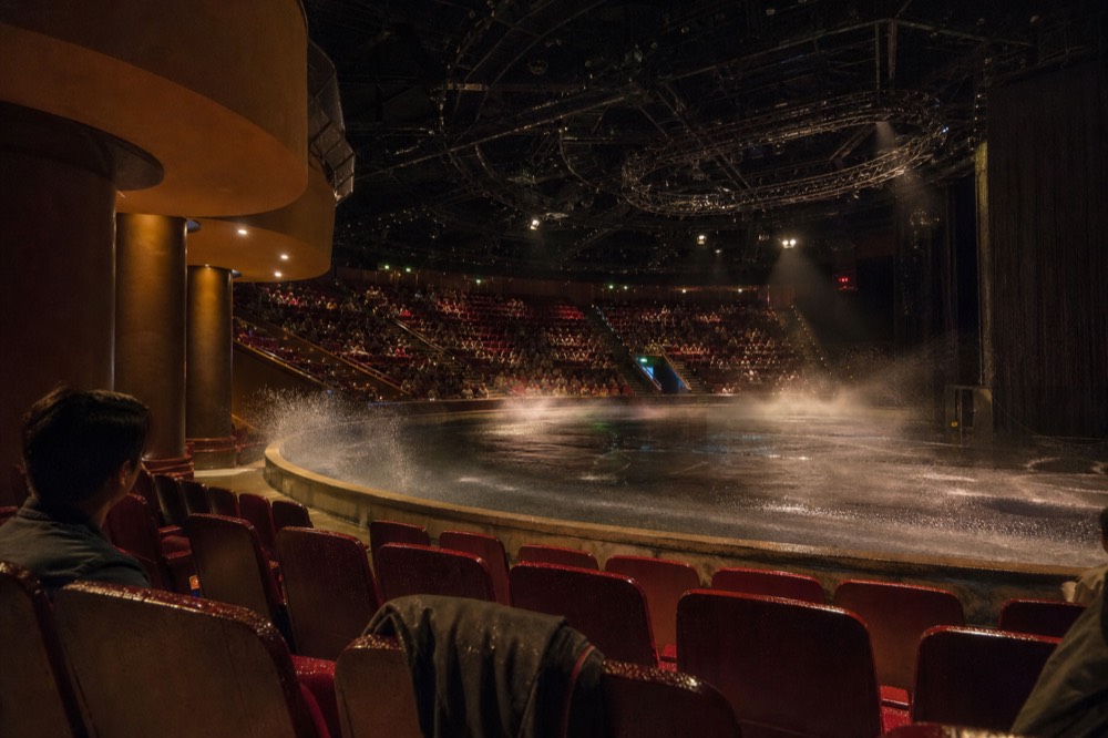 Water droplets and mist rising over the front rows of a theatre surrounding a pool stage