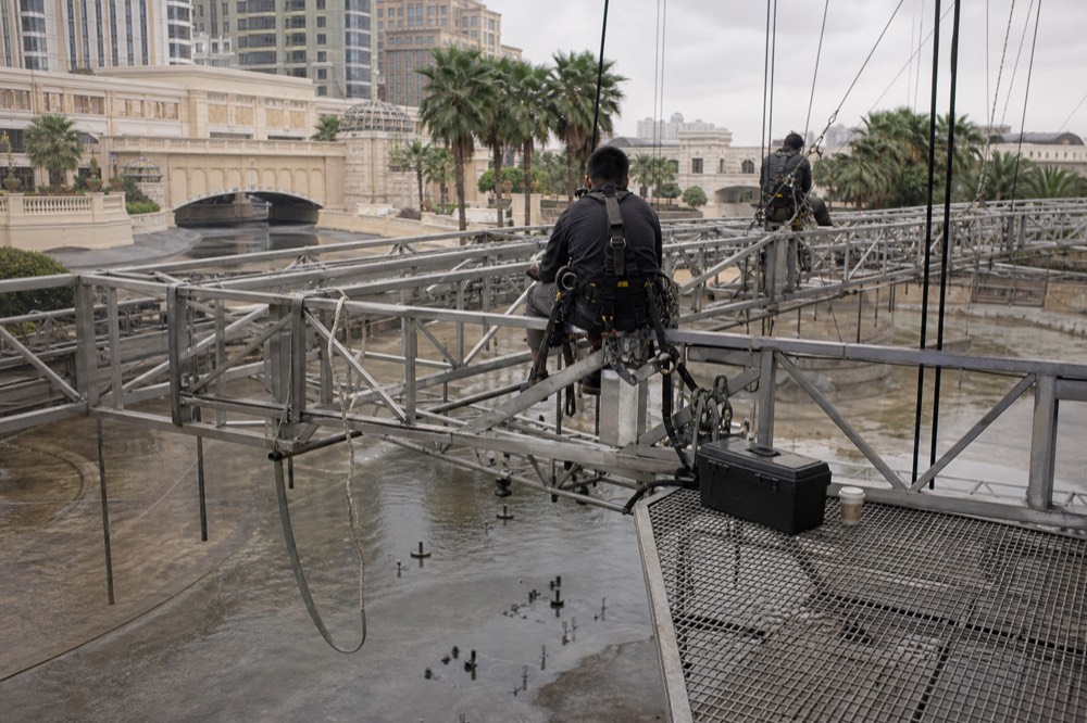 A theatre stage crew preparing equipment above a large pool before a performance