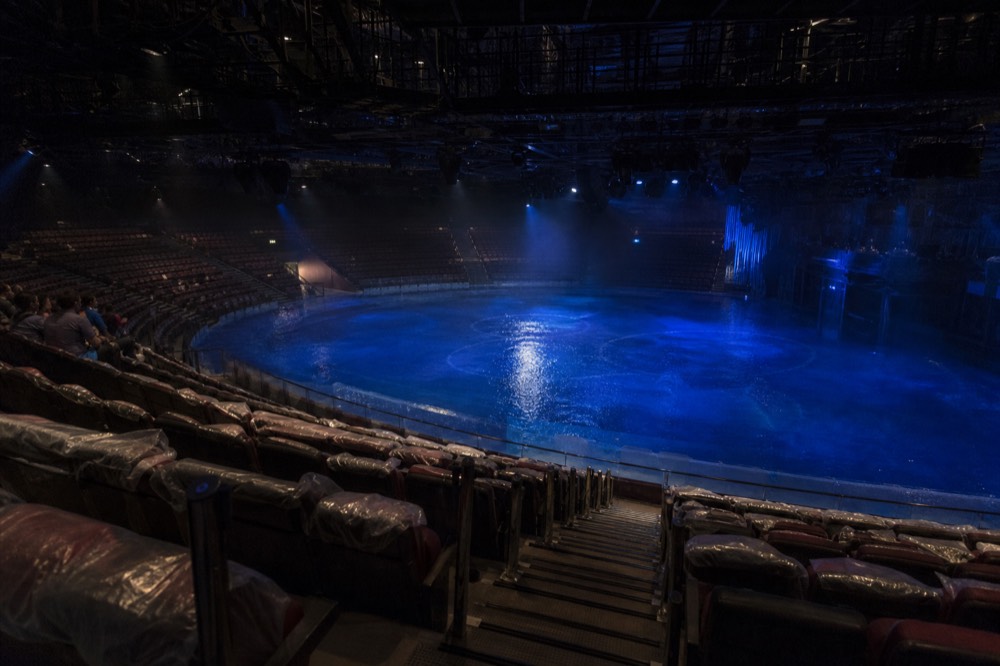 Tiered theatre seating curving around the water stage with the pool visible below
